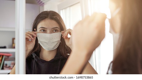 young girl wearing medical protective face mask looking mirror stay at home social dictancing concept - Powered by Shutterstock