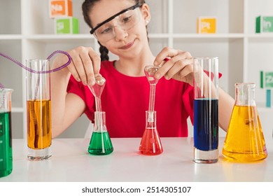 Young girl wearing safety goggles conducting a science experiment with colorful liquids in a laboratory setting. - Powered by Shutterstock