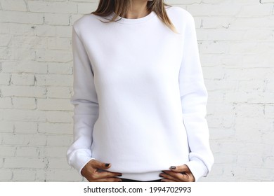 Young  girl wearing white template women's sweatshirt with copy space for your design or logo, mock-up of black cotton sweatshirt, white stone wall in the background.