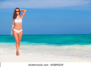 young girl in white bikini walking at tropical beach