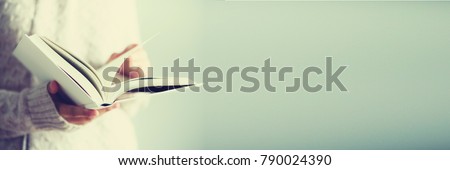 Young girl in white cardigan reading opened book. Copy space. lifestyle and school concept. Banner.