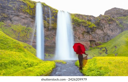 Young girl in white dress holding red umbrella - Amazing Seljalandsfoss waterfall with rainbow - Iceland - Powered by Shutterstock