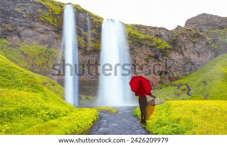 Young girl in white dress holding red umbrella - Amazing Seljalandsfoss waterfall with rainbow - Iceland