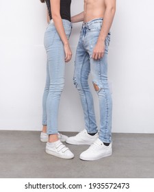 Young girl in white shirt with blue jeans and man in torn blue jeans with white sneaker,shoes on gray background
