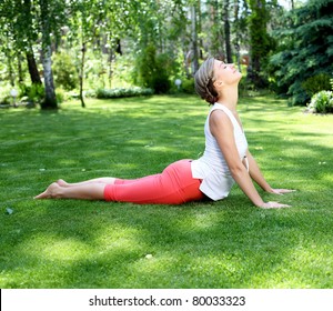 Young Girl In A White Shirt And Red Pants Doing Yoga Outdoors