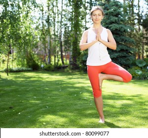 Young Girl In A White Shirt And Red Pants Doing Yoga Outdoors