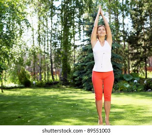 Young Girl In A White Shirt And Red Pants Doing Yoga Outdoors