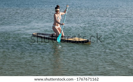 A young girl in a white swimsuit rides a sup Board. Healthy and active lifestyle.