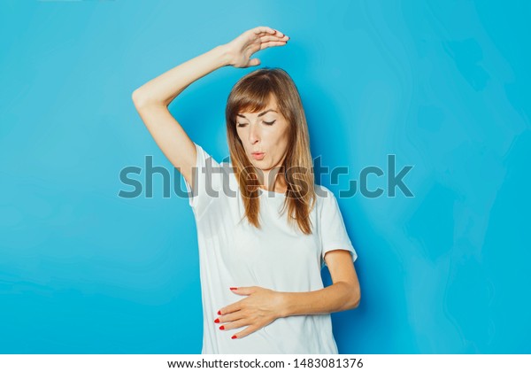青の背景に汗で濡れた腋の下を持つ白いtシャツの若い女の子 過度の発汗 熱 消臭のコンセプト の写真素材 今すぐ編集