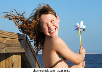 Young girl at windy beach having fun with pinwheel