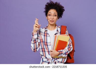 Young Girl Woman Of African American Ethnicity Teen Student In Shirt Backpack Keep Fingers Crossed Making Wish Isolated On Plain Purple Background Education In High School University College Concept