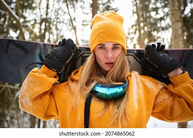 young girl or woman snowboarder goes in for winter sports in snowy forest she stands in snow and holds a snowboard
