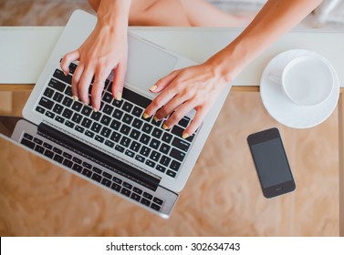 young girl woman working on a laptop sitting at home write messages to drinking coffee smiling typing on a keyboard, macbook serfing, applet style, iphone,