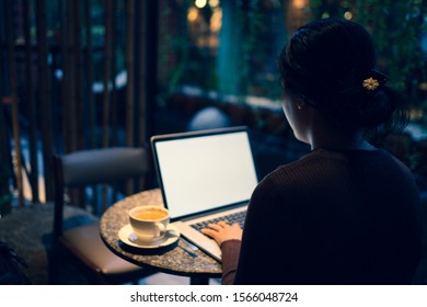 A Young Girl Working With A Cup Of Cappuccino Coffee With Laptop White Screen On Table. Royalty High Quality Free Stock Photo Image Of A Woman Typing, Working On Laptop In A Coffee Shop