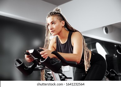 Young girl working out on a bike simulator at a fitness center. Bicycle simulator, great design for any purposes. Fitness training. Healthy lifestyle. Fitness cycle. Fitness workout. Cycle jersey.