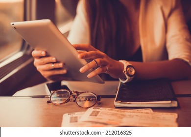 Young girl works on the tablet on the internet and goes to the train, ipad surfing, woman using smartphone, holding tablet in hand, send answer texts, travel in train, office manager, hipster