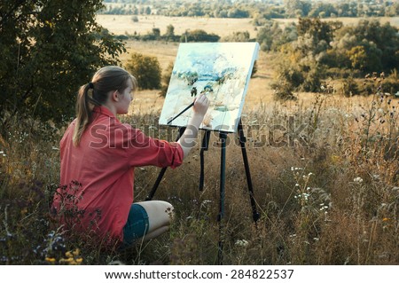 Young girl-artist is painting with watercolor on the plein Air
