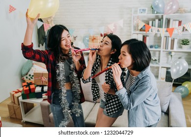 Young Girls Best Friends Celebrating Graduation Party In House. Female Students Playing With Whistles And Balloons Having Fun At Decorated Home. Enjoyment Friendship Never End Concept.