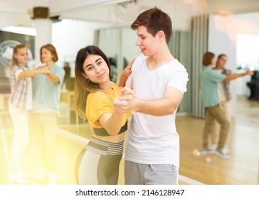 Young girls and boys dancing waltz together in ballroom during group class.