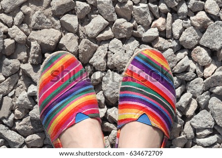 A young girl's  feet with colored shoes on stone. Footwear.