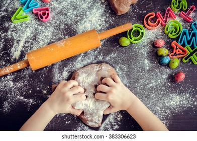 Young girl's hands kneading dough. Easter baking preparation. Close-up of child's hands baking cookies. Easter eggs. Easter food concept. Top view.