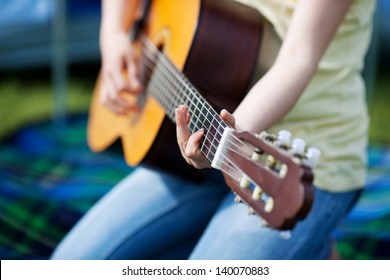 Young Girls Hands Playing Guitar Against Tent