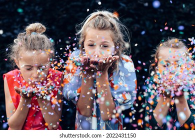 Young Girls Having Fun Celebrating While Blowing Confetti At Party Outdoor - Focus On Center Hands Kid