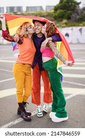 Young Girls Kissing Asian Friend At Gay Pride Parade While Holding LGBT Rainbow Flag