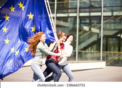 Young girls laughing and walking holding an EU flag