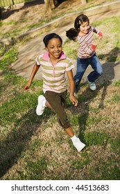 Young Girls Running On Grass. Vertically Framed Shot.