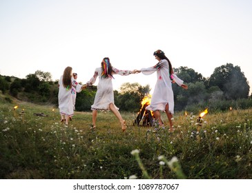 young girls in white shirts and wreaths of flowers on the background of a fire. The celebration of the pagan Slavic holiday of Ivan Kupala Day or Midsummer.
