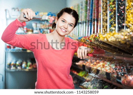 Young glad woman with candies at sweets shop