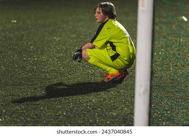 a young goalkeeper girl resting on the field i front of a goal-net, yellow uniform, school football team. High quality photo - Powered by Shutterstock