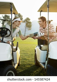 Young Golfers Sitting In Golf Carts Holding Score Card On Course