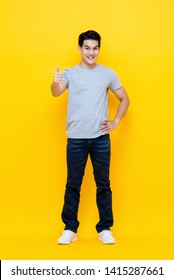 Young Good Looking Asian Man Standing With Thumbs Up Gesture Isolated On Bright Yellow Studio Background