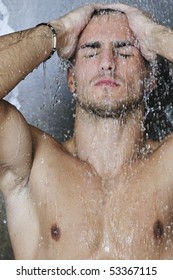 young good looking and attractive man with muscular body wet taking shower in bath with black tiles in background
