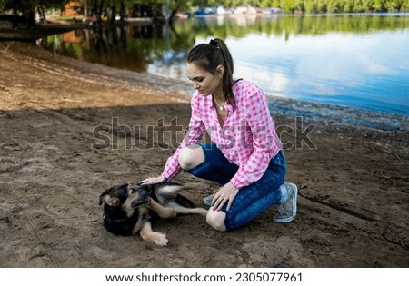 Young and good looking girl walking a little dog in park near lake.