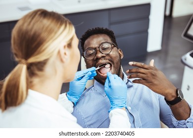 Young Good Looking Man Having Dental Treatment At Dentist's Office. African Guy In Dentist Chair Looking With Trust At His Doctor, Close Up. Man Having Teeth Examined At Dentists. 