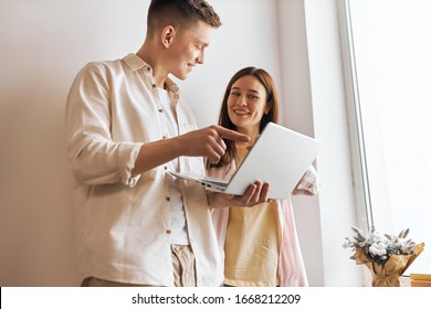young good looking programmer fixing woman's computer, man helping woman to work with laptop, close up photo. man pointing to the screen