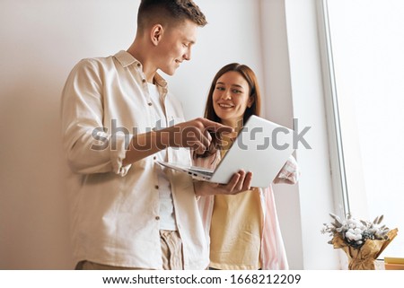 young good looking programmer fixing woman's computer, man helping woman to work with laptop, close up photo. man pointing to the screen