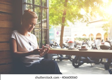 Young gorgeous lady chatting on her smart phone while relaxing in cafe after walking during summer weekend, attractive woman reading text message on cell telephone while sitting in cozy coffee shop  - Powered by Shutterstock