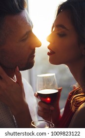 Young gorgeous woman with glass of wine kissing her man in sunset స్టాక్ ఫోటో