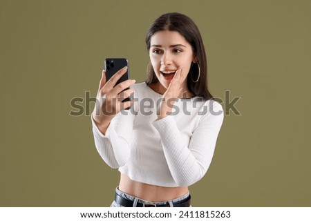 Young gossip woman with mobile phone on green background