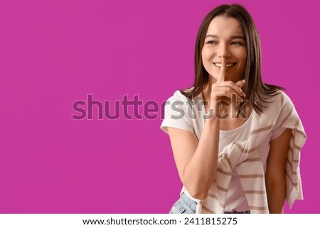 Young gossip woman showing silence gesture on purple background