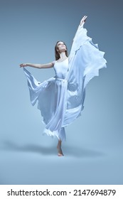 A young graceful ballerina in a delicate white dress flies in a jump. Ballet, dance inspiration. Full-length studio portrait. 