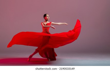 young graceful ballerina, dressed in pointe shoes and a weightless red skirt, demonstrates her dancing skills. The beauty of classical ballet. - Powered by Shutterstock