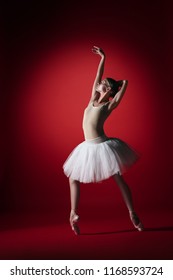 Young graceful female ballet dancer or classic ballerina dancing at red studio. Caucasian model on pointe shoes - Shutterstock ID 1168593724