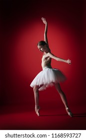 Young graceful female ballet dancer or classic ballerina dancing at red studio. Caucasian model on pointe shoes - Shutterstock ID 1168593727