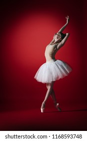Young graceful female ballet dancer or classic ballerina dancing at red studio. Caucasian model on pointe shoes - Shutterstock ID 1168593748
