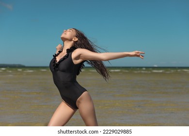 young graceful and flexible gymnast in swimsuit flexibility by the sea